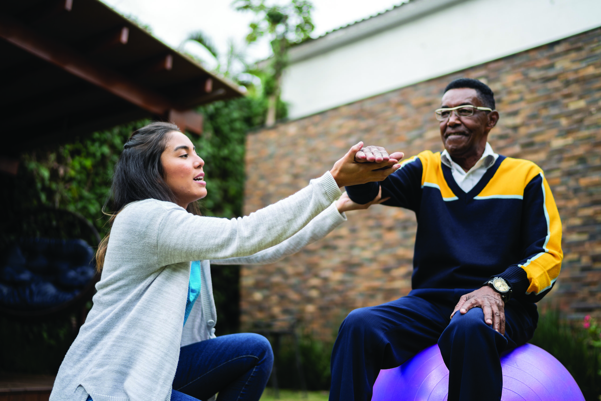 Senior man doing exercise lifting arms with physical therapist at home