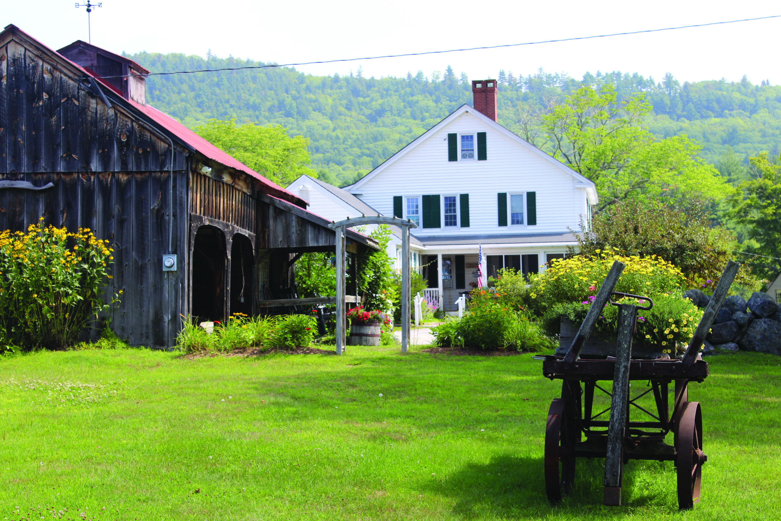 photo of the outside of Robin Hill Farm with nature and a wheelbarrow