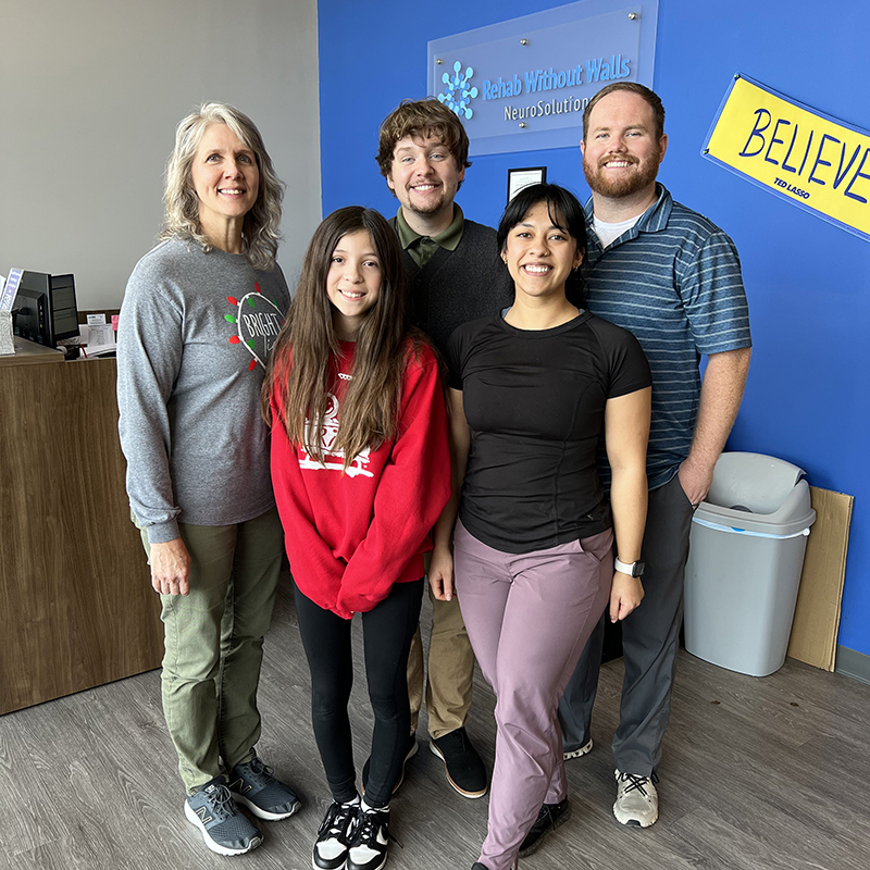 Patient Bella is standing in front of her therapy team